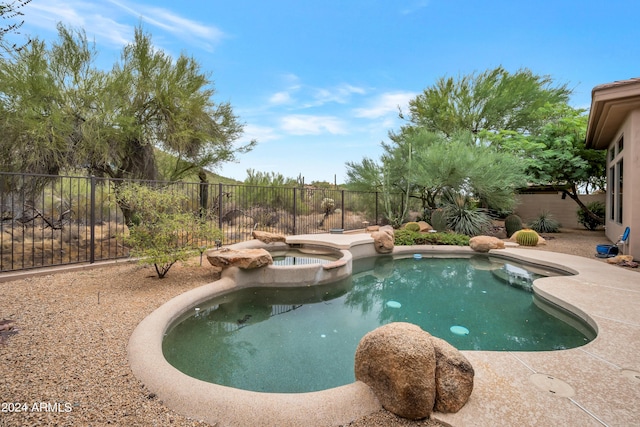 view of swimming pool featuring a pool with connected hot tub and a fenced backyard