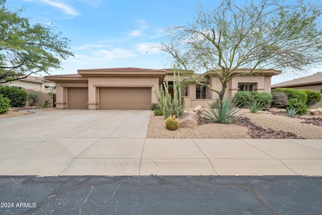 view of front of house with stucco siding, driveway, a tile roof, and a garage