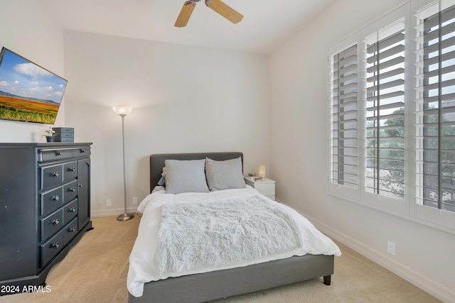 bedroom with light colored carpet, a ceiling fan, and baseboards