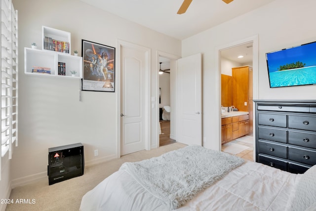 bedroom with ceiling fan, light colored carpet, baseboards, and connected bathroom