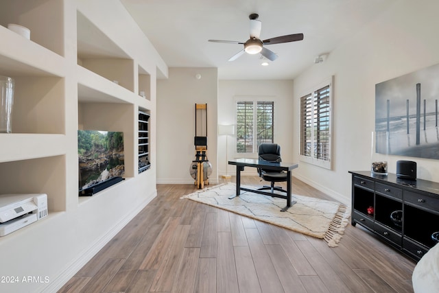 living room with built in features, wood-type flooring, and ceiling fan