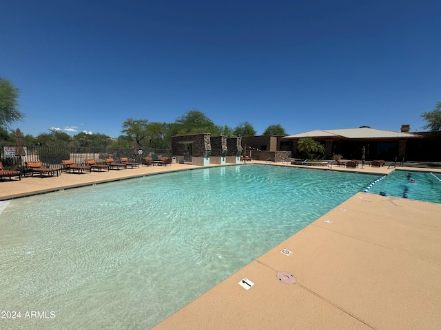 pool with a patio area and fence