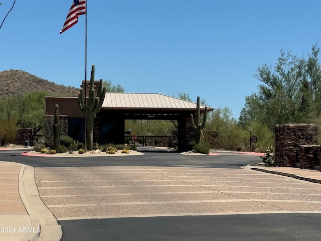 view of street featuring curbs, a mountain view, a gated entry, and traffic signs