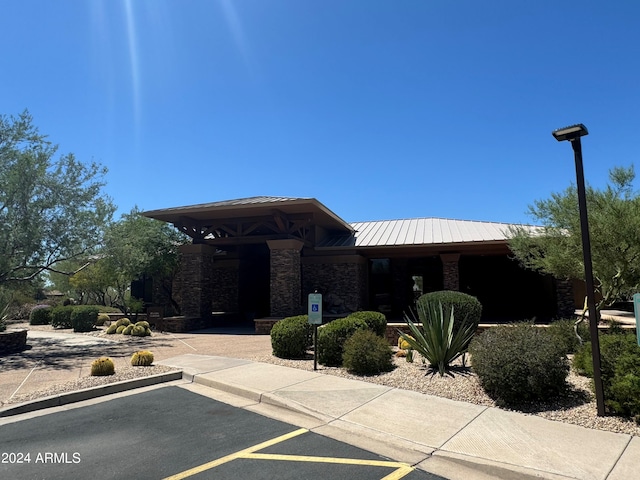 view of front facade with metal roof, stone siding, uncovered parking, and a standing seam roof