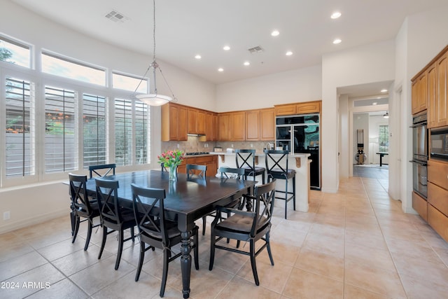 dining room with light tile patterned floors, visible vents, recessed lighting, and a towering ceiling