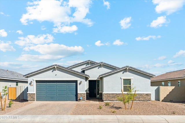 single story home featuring an attached garage, fence, stone siding, decorative driveway, and stucco siding