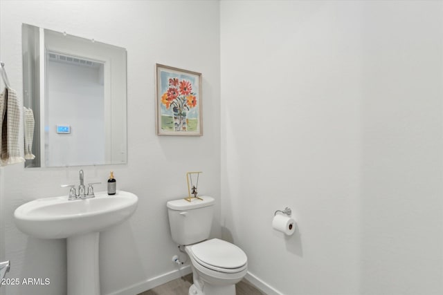 half bath with baseboards, toilet, and wood finished floors