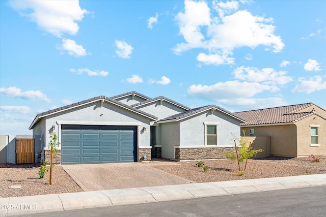 view of front of property with a garage, stone siding, a tiled roof, decorative driveway, and stucco siding