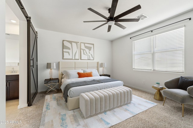 bedroom featuring a barn door, connected bathroom, a sink, visible vents, and baseboards