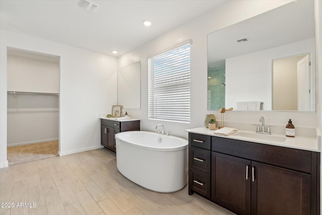 bathroom with visible vents, a tile shower, a sink, and wood finished floors