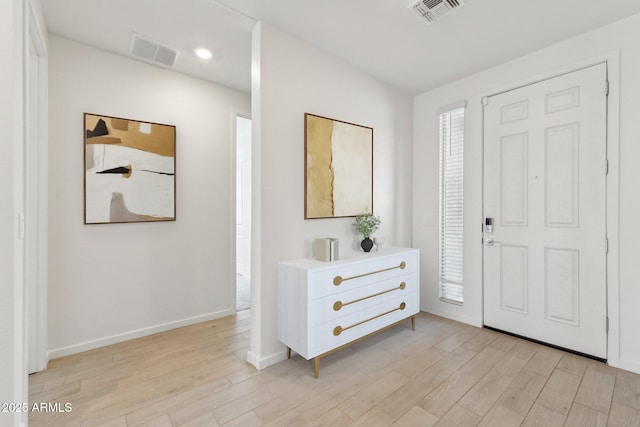 entryway with light wood finished floors, baseboards, and visible vents