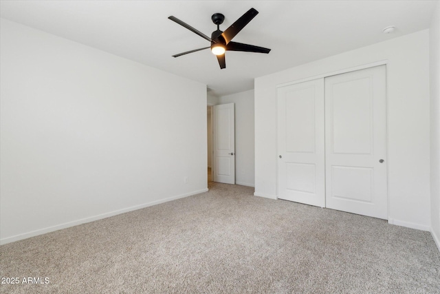 unfurnished bedroom featuring ceiling fan, a closet, carpet flooring, and baseboards