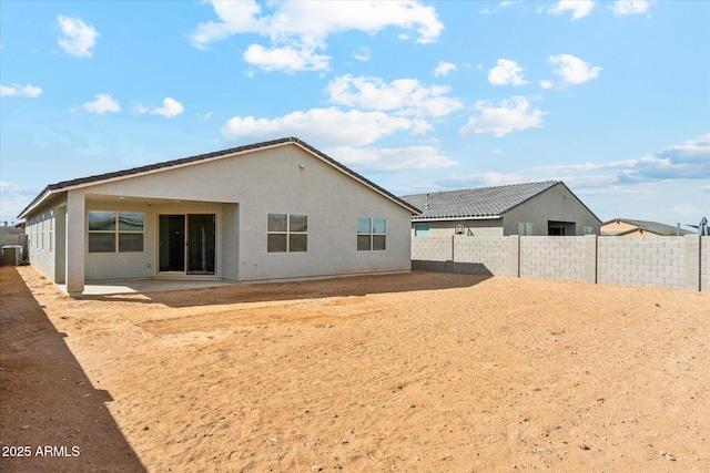 rear view of property featuring central AC unit, a patio area, a fenced backyard, and stucco siding