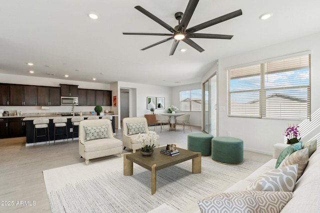 living area with a ceiling fan, recessed lighting, light wood-type flooring, and baseboards