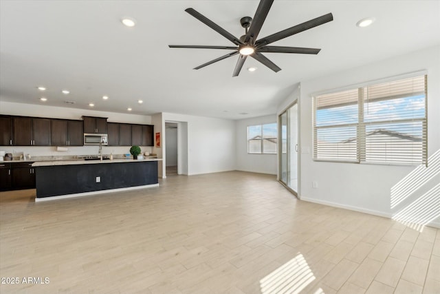 unfurnished living room featuring light wood-type flooring, baseboards, a ceiling fan, and recessed lighting