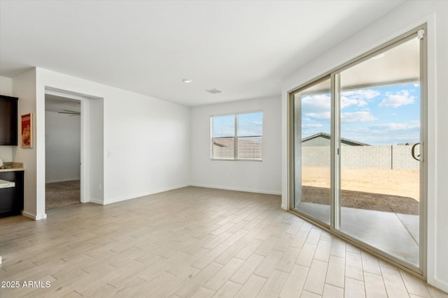 unfurnished room with light wood-style floors, visible vents, and baseboards