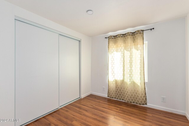 50858 W Bitter Root Rd, Maricopa, AZ 85139 - unfurnished bedroom featuring a closet, baseboards, and wood finished floors