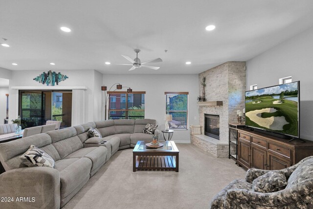 living room featuring ceiling fan, a fireplace, and light carpet