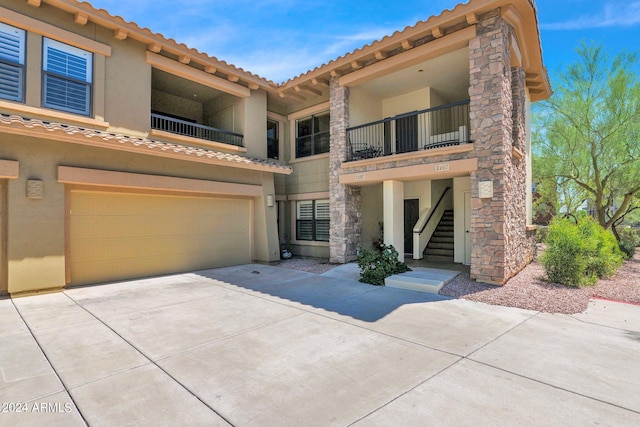 view of front of property featuring concrete driveway, stairway, an attached garage, and stucco siding