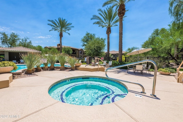 pool featuring a community hot tub, a patio, and fence