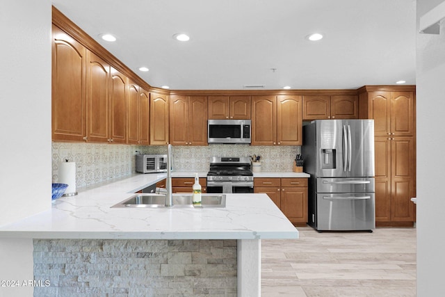 kitchen featuring a peninsula, appliances with stainless steel finishes, decorative backsplash, and light stone counters