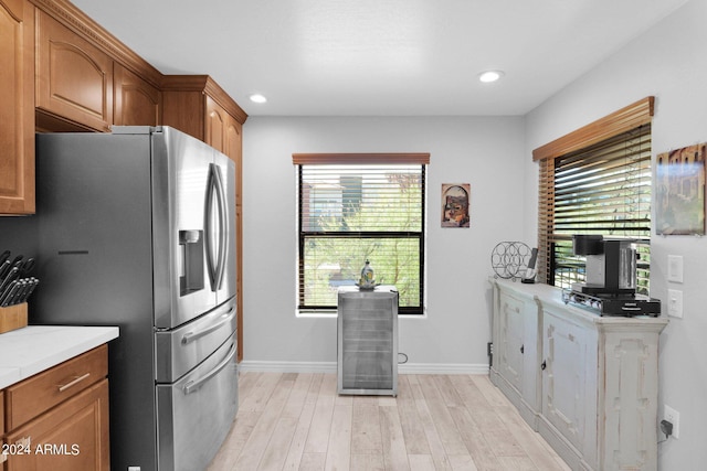 kitchen with recessed lighting, baseboards, light wood-style floors, brown cabinets, and stainless steel fridge