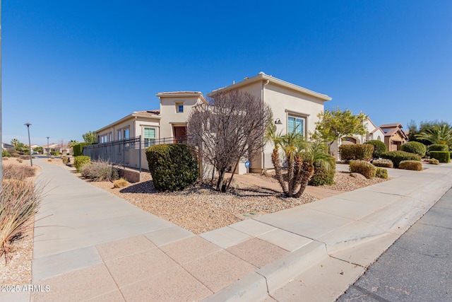 view of side of property featuring a residential view, fence, and stucco siding