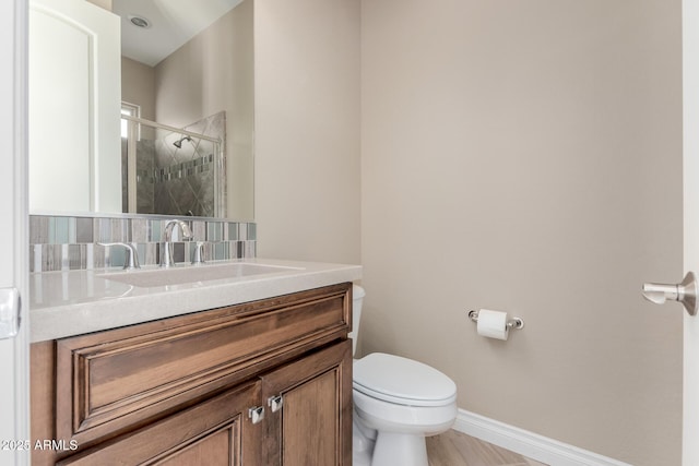 full bathroom featuring a stall shower, baseboards, vanity, and toilet