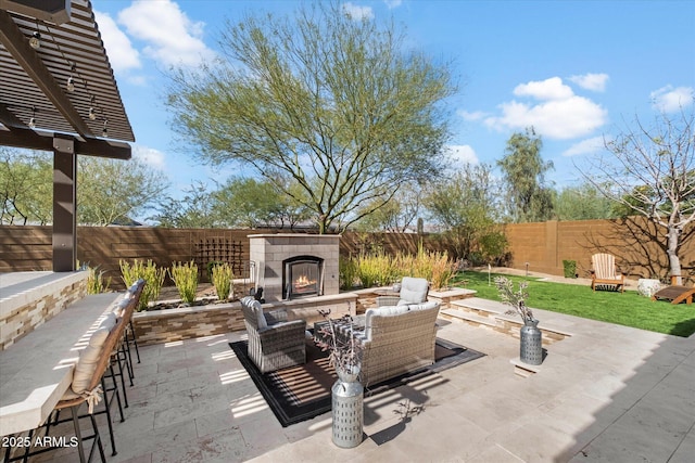 view of patio / terrace featuring a fenced backyard and an outdoor living space with a fireplace