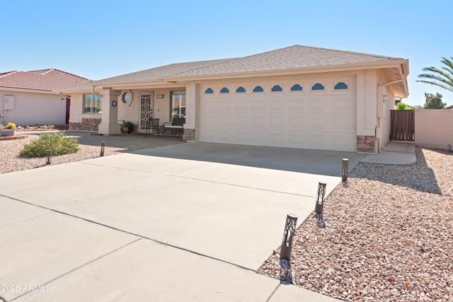 ranch-style house with an attached garage, stone siding, concrete driveway, and stucco siding