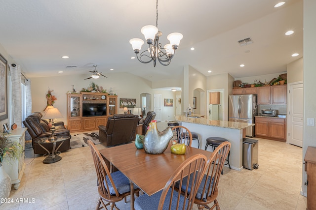 dining room with light tile patterned flooring, ceiling fan with notable chandelier, vaulted ceiling, and sink