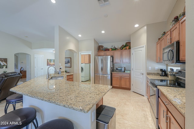 kitchen with a breakfast bar, appliances with stainless steel finishes, washer / clothes dryer, and sink