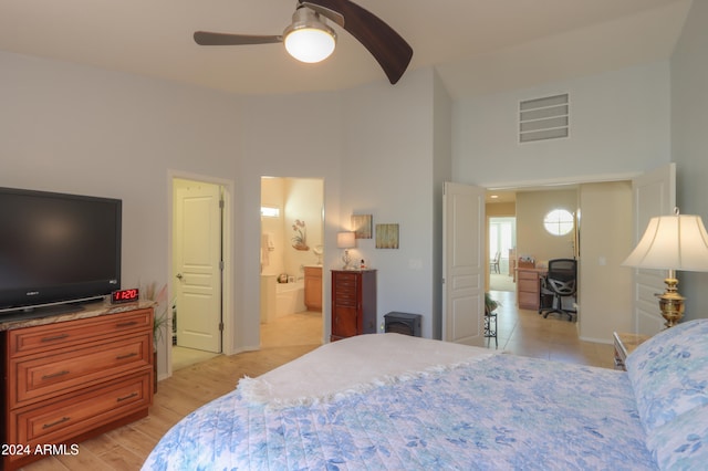 bedroom featuring ceiling fan, light hardwood / wood-style flooring, a towering ceiling, and ensuite bathroom