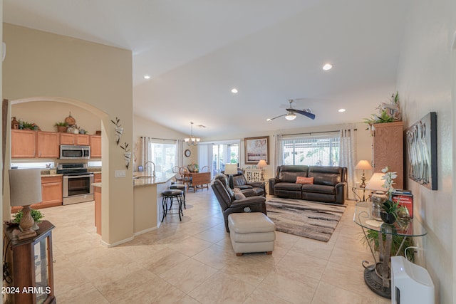 living room with ceiling fan with notable chandelier, a healthy amount of sunlight, lofted ceiling, and sink