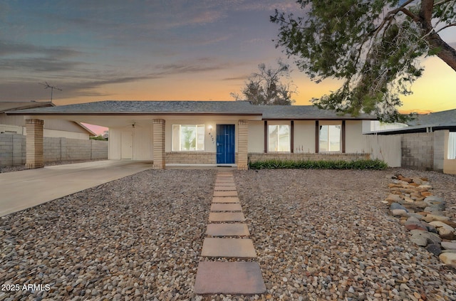 ranch-style house with an attached carport, fence, a shingled roof, concrete driveway, and brick siding