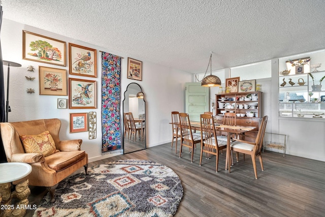 dining space featuring a textured ceiling, baseboards, and wood finished floors