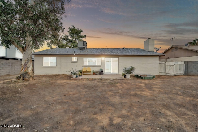 back of property at dusk featuring a patio area, central AC, a chimney, and fence