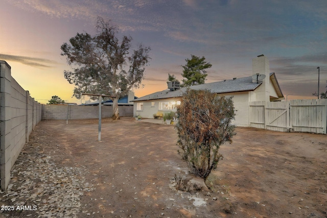 yard at dusk with a fenced backyard and a gate