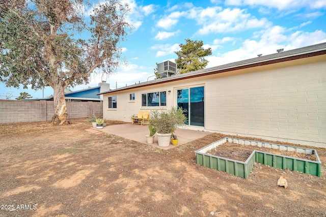 back of house featuring fence, central air condition unit, a chimney, a patio area, and a vegetable garden