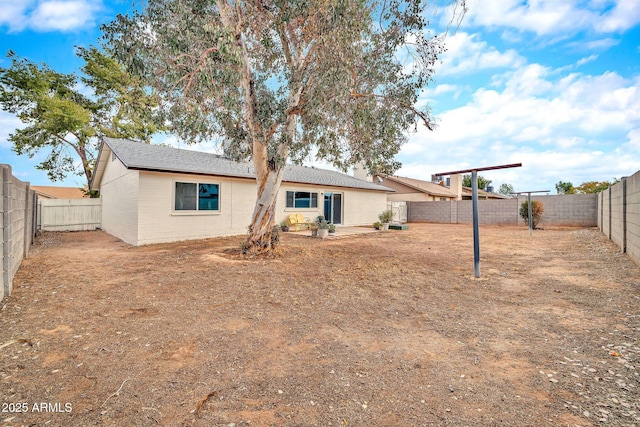 back of house with concrete block siding and a fenced backyard