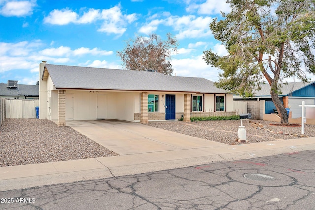 ranch-style house with an attached carport, concrete driveway, and fence