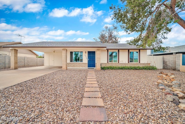 ranch-style house featuring an attached carport, fence, a shingled roof, concrete driveway, and brick siding