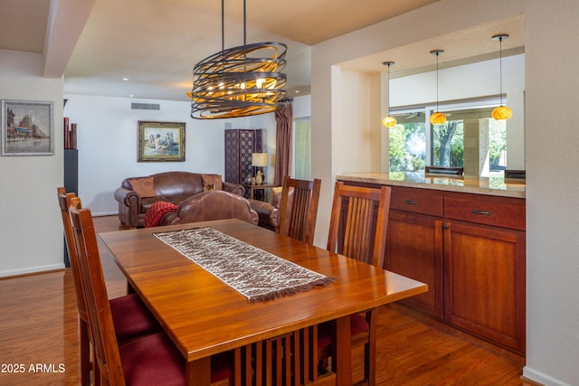 dining space with wood finished floors, visible vents, and baseboards