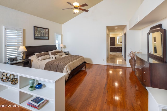 bedroom with high vaulted ceiling, visible vents, connected bathroom, and wood finished floors