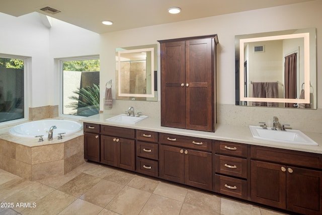 bathroom with a garden tub, visible vents, and a sink