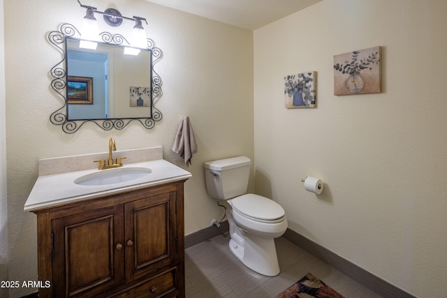 bathroom featuring baseboards, vanity, and toilet