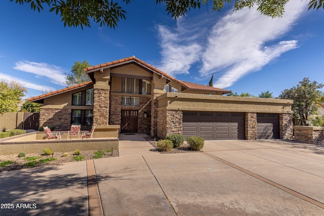 view of front of house featuring a garage, concrete driveway, stone siding, a tiled roof, and stucco siding