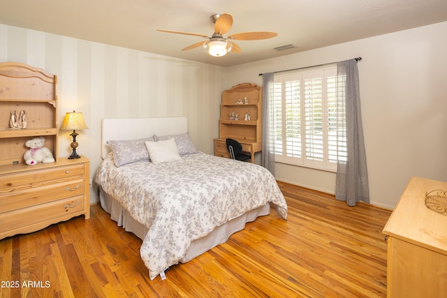 bedroom with ceiling fan, visible vents, baseboards, light wood-type flooring, and wallpapered walls