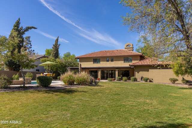 rear view of property featuring a patio, a yard, stucco siding, fence, and a tiled roof