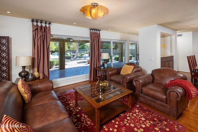 living area with a textured ceiling, visible vents, wood finished floors, and recessed lighting